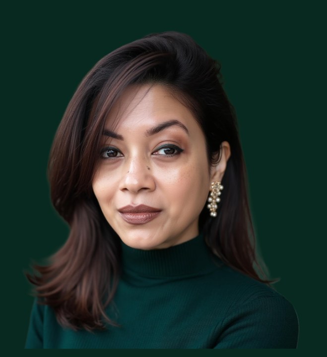 Moumita Bhattacharya, head and shoulders, facing the camera with a slight smile. She has shoulder-length dark hair swept to one side, and wears a dark green turtleneck and pearl drop earrings.
